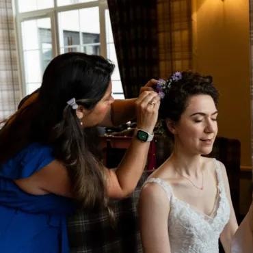 Stylist placing flowers in bride's hair