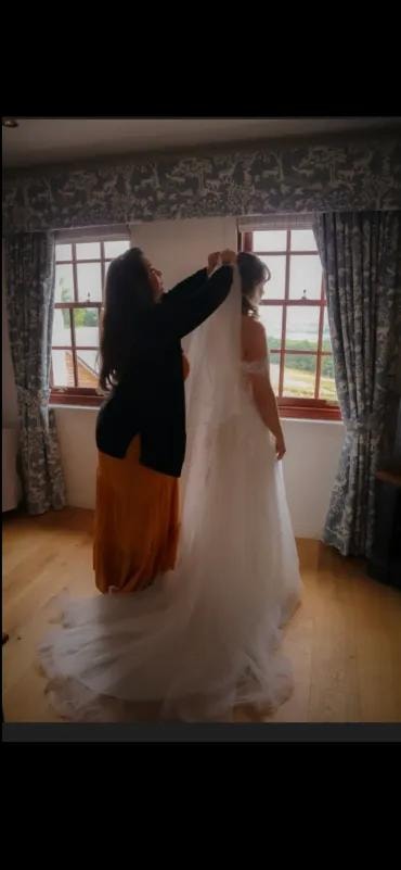 Stylist arranging bride's veil by window